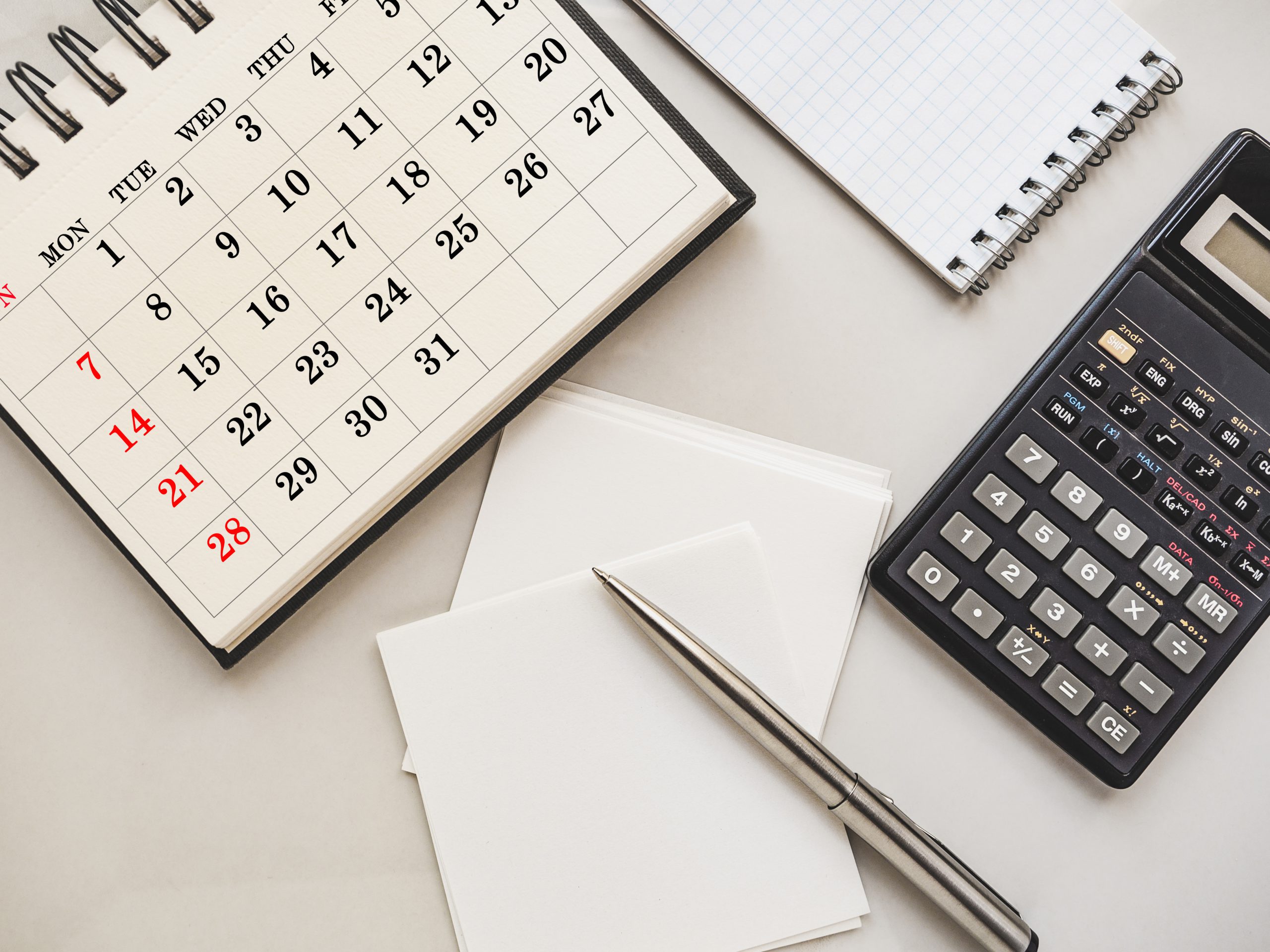 A classic deadline calculator: a pen, paper, calendar, and calculator.